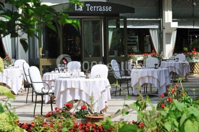Salle de restaurant élégante avec grandes baies vitrées, tables dressées et luminaires suspendus au plafond.