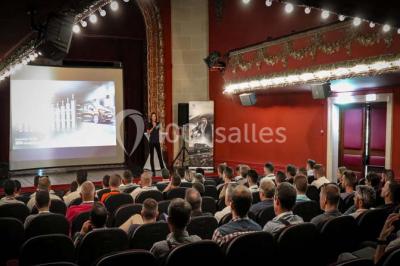 Salle de restaurant élégante avec grandes baies vitrées, tables dressées et luminaires suspendus au plafond.