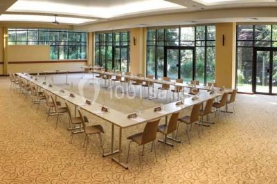 Salle de restaurant élégante avec grandes baies vitrées, tables dressées et luminaires suspendus au plafond.