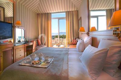 Salle de restaurant élégante avec grandes baies vitrées, tables dressées et luminaires suspendus au plafond.