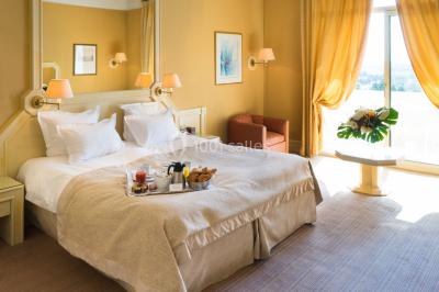 Salle de restaurant élégante avec grandes baies vitrées, tables dressées et luminaires suspendus au plafond.