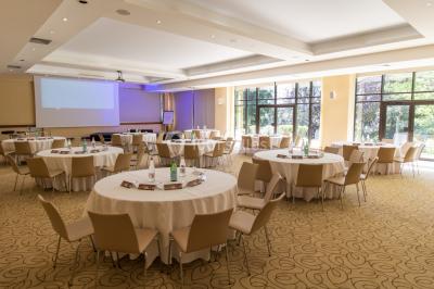 Salle de restaurant élégante avec grandes baies vitrées, tables dressées et luminaires suspendus au plafond.