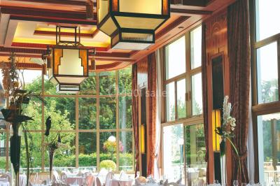 Salle de restaurant élégante avec grandes baies vitrées, tables dressées et luminaires suspendus au plafond.