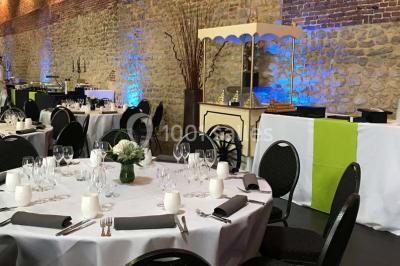Groupe de personnes discutant dans un jardin sous des parasols, avec des tables hautes recouvertes de nappes noires.
