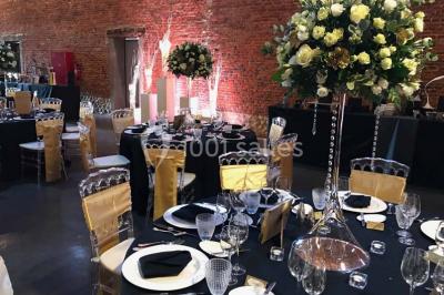 Groupe de personnes discutant dans un jardin sous des parasols, avec des tables hautes recouvertes de nappes noires.