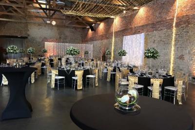 Groupe de personnes discutant dans un jardin sous des parasols, avec des tables hautes recouvertes de nappes noires.