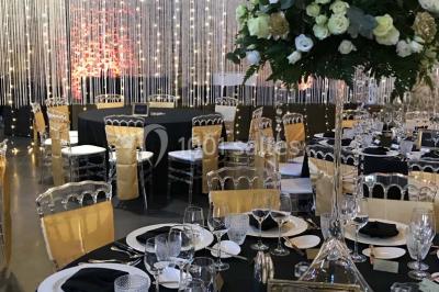 Groupe de personnes discutant dans un jardin sous des parasols, avec des tables hautes recouvertes de nappes noires.