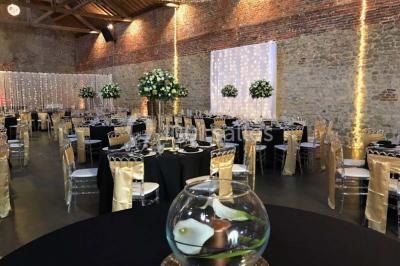 Groupe de personnes discutant dans un jardin sous des parasols, avec des tables hautes recouvertes de nappes noires.