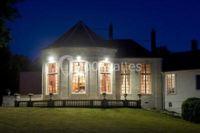Un parc de nuit avec des arbres sombres, une structure lumineuse orange et des chemins faiblement éclairés.