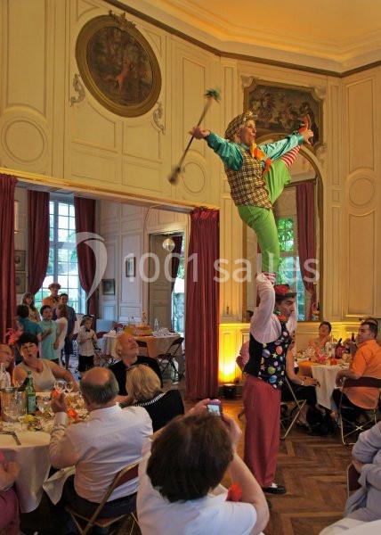 Un acrobate en costume coloré réalise une figure sur les épaules d'un partenaire dans une salle de réception.