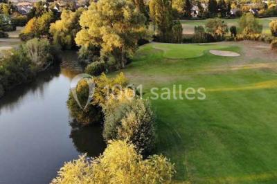 Vue d'un terrain de golf avec un green bien entretenu, entouré d'arbres et éclairé par une lumière douce en fin de journée.