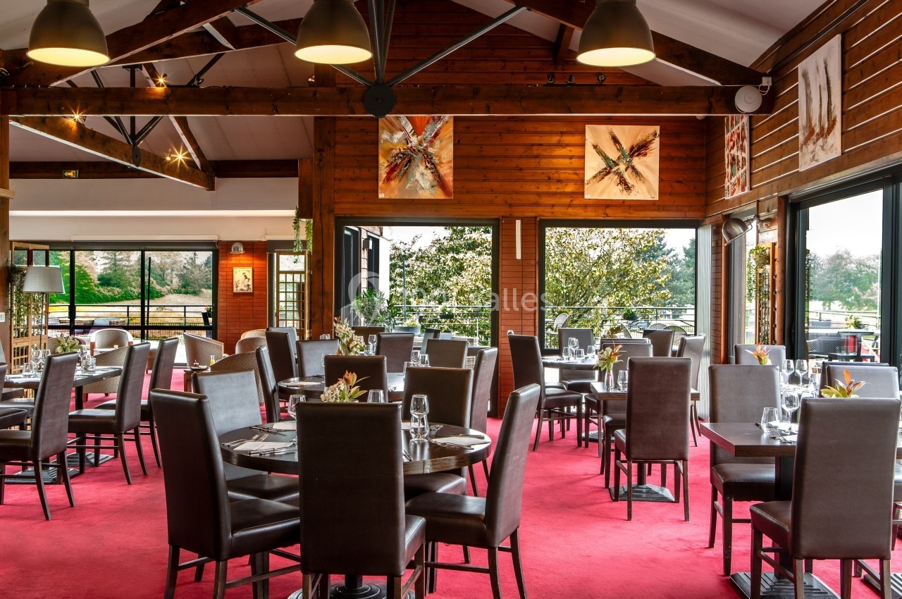 Salle de restaurant lumineuse avec tables dressées, chaises en cuir marron, grandes baies vitrées et décorations murales.