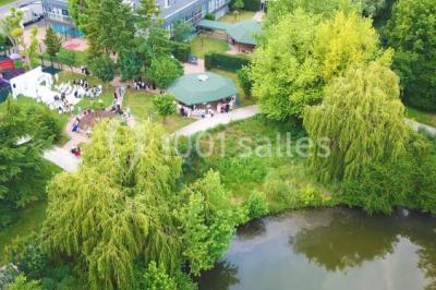 Bâtiment blanc moderne à deux étages avec colonnes, grandes fenêtres et espace paysager à l'avant.