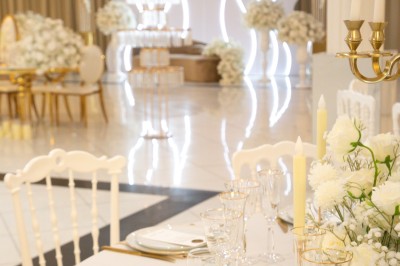 Bâtiment blanc moderne à deux étages avec colonnes, grandes fenêtres et espace paysager à l'avant.