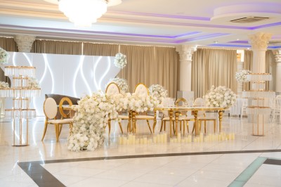 Bâtiment blanc moderne à deux étages avec colonnes, grandes fenêtres et espace paysager à l'avant.