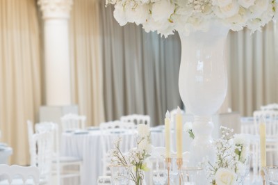 Bâtiment blanc moderne à deux étages avec colonnes, grandes fenêtres et espace paysager à l'avant.