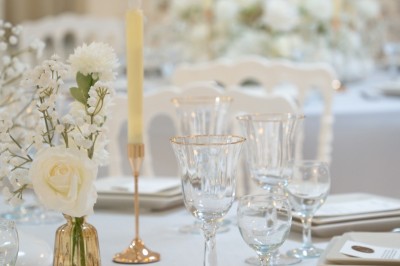 Bâtiment blanc moderne à deux étages avec colonnes, grandes fenêtres et espace paysager à l'avant.