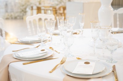 Bâtiment blanc moderne à deux étages avec colonnes, grandes fenêtres et espace paysager à l'avant.