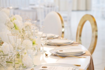 Bâtiment blanc moderne à deux étages avec colonnes, grandes fenêtres et espace paysager à l'avant.