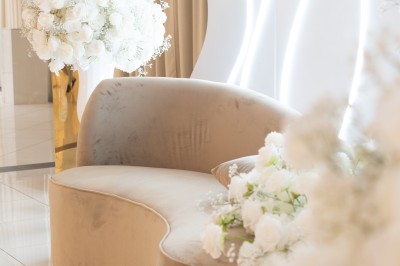 Bâtiment blanc moderne à deux étages avec colonnes, grandes fenêtres et espace paysager à l'avant.