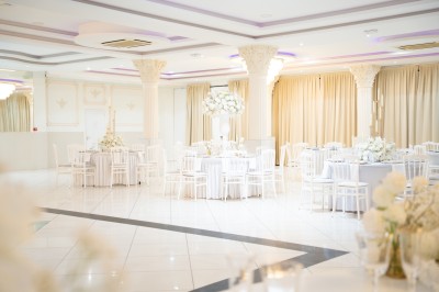 Bâtiment blanc moderne à deux étages avec colonnes, grandes fenêtres et espace paysager à l'avant.