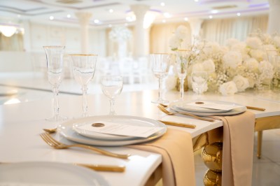 Bâtiment blanc moderne à deux étages avec colonnes, grandes fenêtres et espace paysager à l'avant.