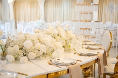 Bâtiment blanc moderne à deux étages avec colonnes, grandes fenêtres et espace paysager à l'avant.