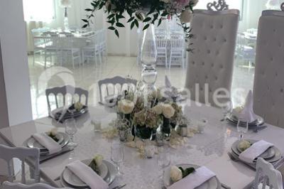 Buffet de desserts avec macarons colorés, verrines et pâtisseries disposés sur des présentoirs décoratifs dans une salle…