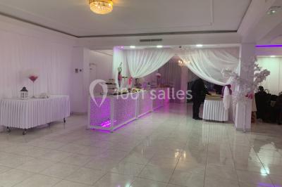 Buffet de desserts avec macarons colorés, verrines et pâtisseries disposés sur des présentoirs décoratifs dans une salle…