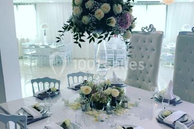 Buffet de desserts avec macarons colorés, verrines et pâtisseries disposés sur des présentoirs décoratifs dans une salle…