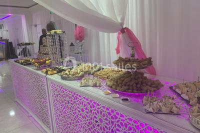 Buffet de desserts avec macarons colorés, verrines et pâtisseries disposés sur des présentoirs décoratifs dans une salle…