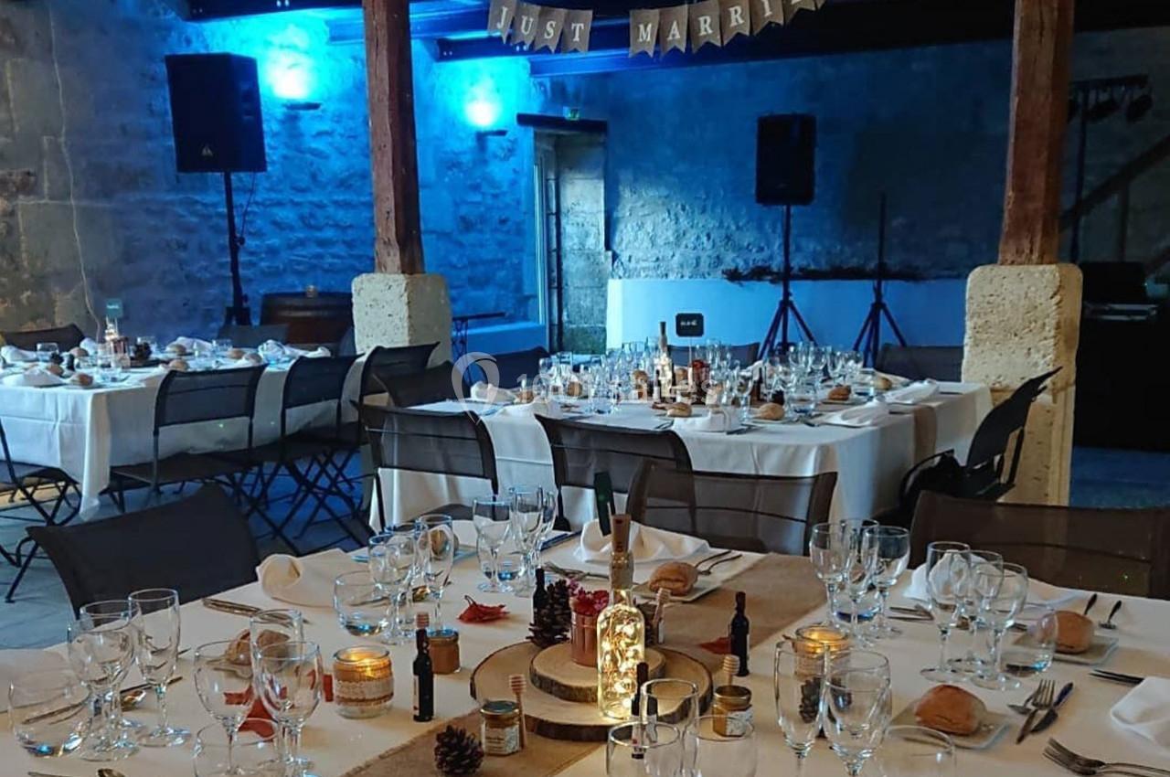 Salle décorée pour un mariage avec tables dressées, guirlande ’Just Married’ et éclairage bleu en arrière-plan.