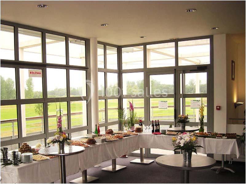 Buffet dressé dans une salle lumineuse avec de grandes baies vitrées donnant sur un espace extérieur verdoyant.