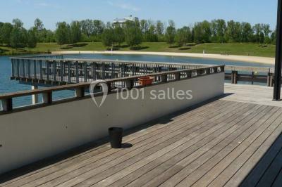 Terrasse en bois avec mobilier de jardin, parasol et vue sur un terrain de golf verdoyant par temps ensoleillé.