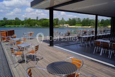 Terrasse en bois avec mobilier de jardin, parasol et vue sur un terrain de golf verdoyant par temps ensoleillé.