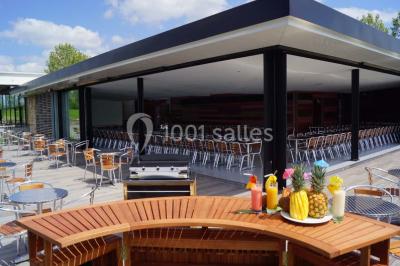 Terrasse en bois avec mobilier de jardin, parasol et vue sur un terrain de golf verdoyant par temps ensoleillé.