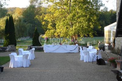 Salle lumineuse avec une grande table rectangulaire couverte d'une nappe bleue, entourée de chaises rouges, et une fenêtre…