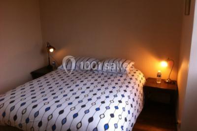 Salle lumineuse avec une grande table rectangulaire couverte d'une nappe bleue, entourée de chaises rouges, et une fenêtre…