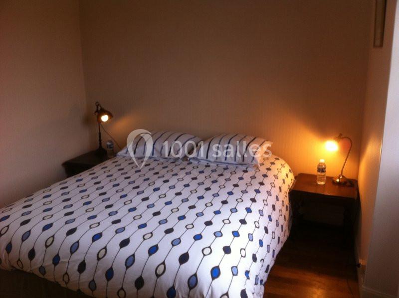 Lit double avec une housse de couette à motifs géométriques, encadré par deux tables de chevet avec lampes allumées.