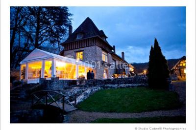 Salle lumineuse avec une grande table rectangulaire couverte d'une nappe bleue, entourée de chaises rouges, et une fenêtre…