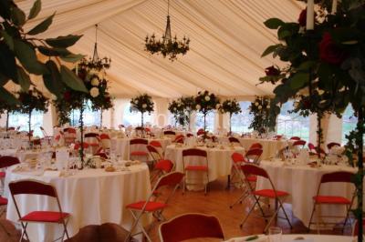 Salle lumineuse avec une grande table rectangulaire couverte d'une nappe bleue, entourée de chaises rouges, et une fenêtre…