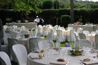 Salle lumineuse avec une grande table rectangulaire couverte d'une nappe bleue, entourée de chaises rouges, et une fenêtre…
