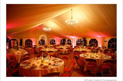Salle lumineuse avec une grande table rectangulaire couverte d'une nappe bleue, entourée de chaises rouges, et une fenêtre…