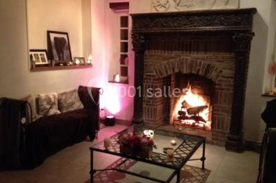 Salle lumineuse avec une grande table rectangulaire couverte d'une nappe bleue, entourée de chaises rouges, et une fenêtre…