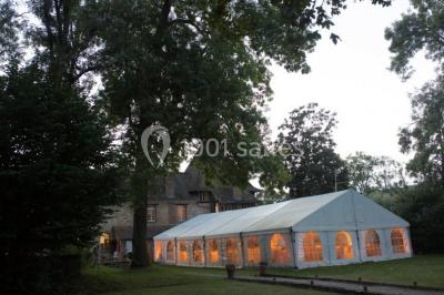 Salle lumineuse avec une grande table rectangulaire couverte d'une nappe bleue, entourée de chaises rouges, et une fenêtre…