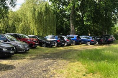 Salle lumineuse avec une grande table rectangulaire couverte d'une nappe bleue, entourée de chaises rouges, et une fenêtre…