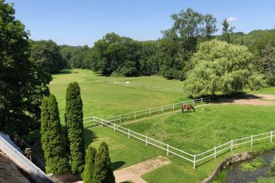 Salle lumineuse avec une grande table rectangulaire couverte d'une nappe bleue, entourée de chaises rouges, et une fenêtre…