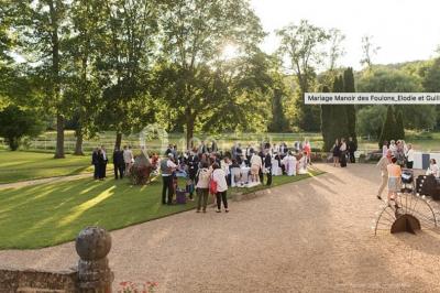 Salle lumineuse avec une grande table rectangulaire couverte d'une nappe bleue, entourée de chaises rouges, et une fenêtre…