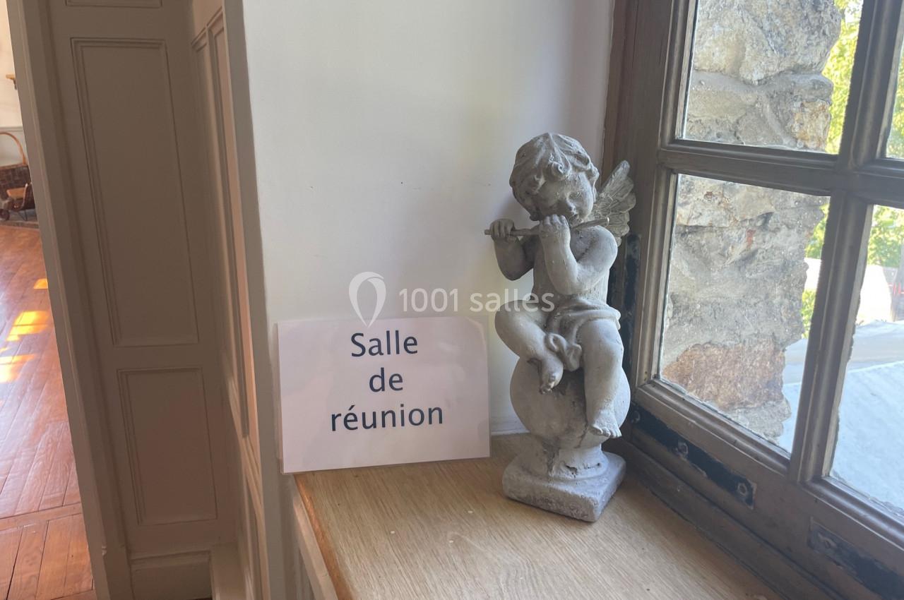Statue d'ange jouant de la flûte posée sur un rebord de fenêtre près d'un panneau ’Salle de réunion’.
