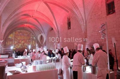 Chambre lumineuse avec lit double, mur beige capitonné, bureau minimaliste, chaise jaune et fenêtre à croisillons.